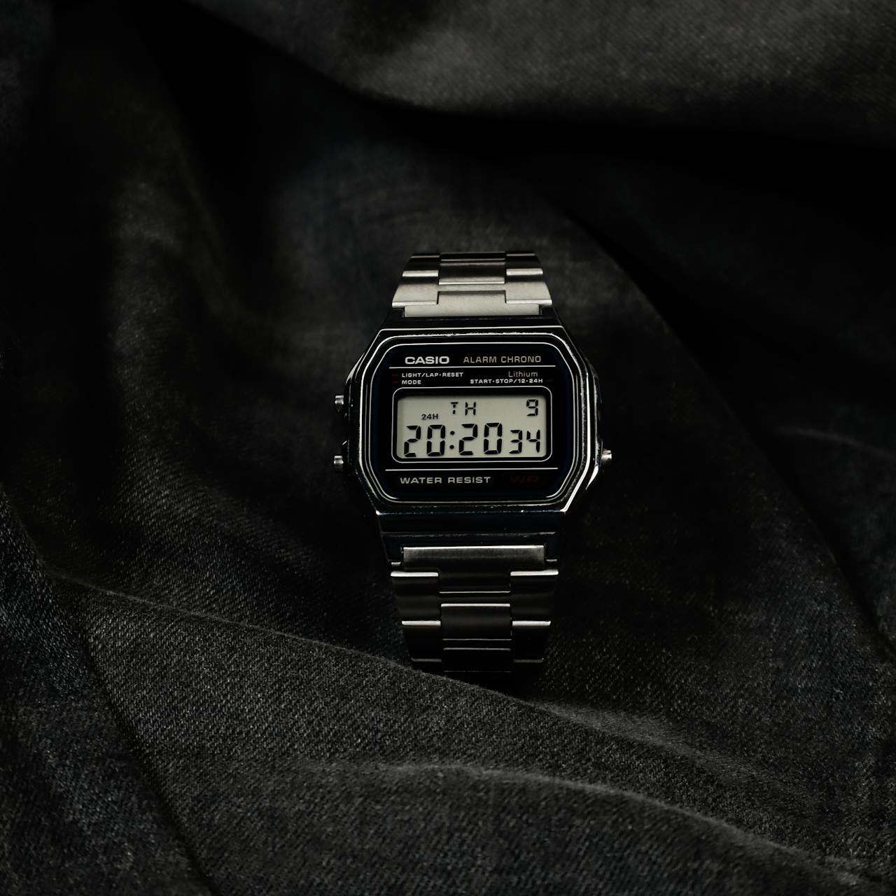Digital wristwatch displayed elegantly on dark fabric, highlighting its modern design.